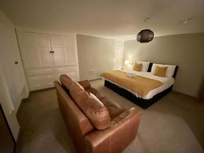 A bedroom with a bed, a sofa, and a wardrobe.