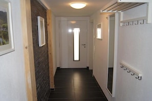 A narrow hallway with a door at the end, a light fixture on the ceiling, and a coat rack on the wall. - Holiday apartment with 2 bedrooms (Bernkastel-Andel)