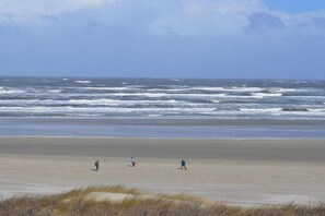 Ein Strand mit Wellen und drei Personen.