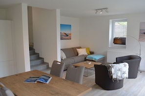 Ein moderner Wohnraum mit Esstisch, Sofa und einer Treppe zu einer weiteren Ebene.