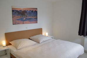 Ein Schlafzimmer mit einem Bett, zwei Nachttischen, einem Beistelltisch und einem Bild an der Wand.