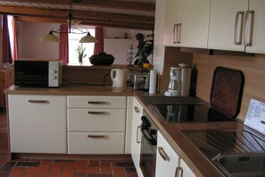 A kitchen with a microwave, coffee maker, and a sink. There are cabinets and a countertop. - Holiday apartment with 1 bedroom (Krummhörn-Eilsum)