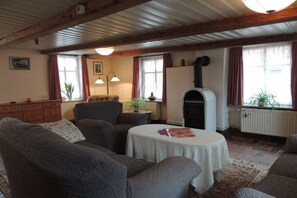 Ein gemütliches Wohnzimmer mit Kamin, einer Couch, einem Tisch mit Unterlage und einer Heizung.