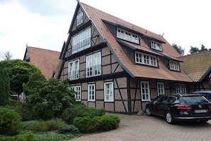 A traditional half-timbered house with a steeply pitched roof, multiple windows, and a parked car in the driveway. - Holiday apartment in Hambühren with barbecue (Hambühren)