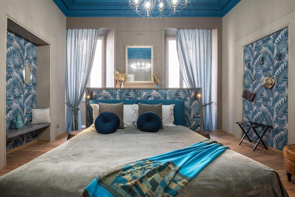 A bedroom with a large bed, a chandelier, and a view of the outdoors.