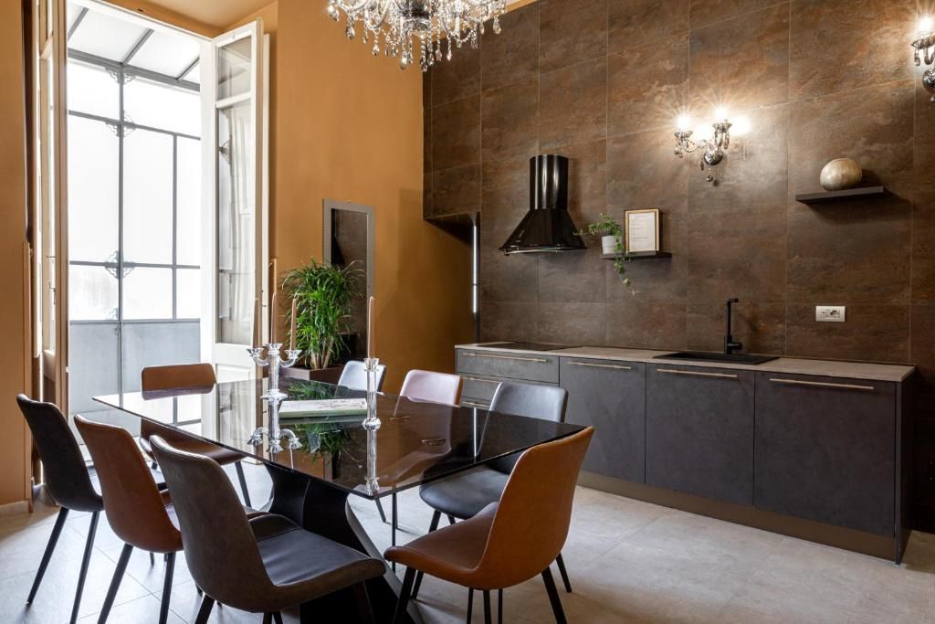 A modern kitchen with a dining table and chairs, a chandelier, and a large window.
