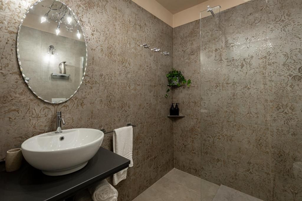 A bathroom with a round mirror, a sink, a towel rack, and a shower area.