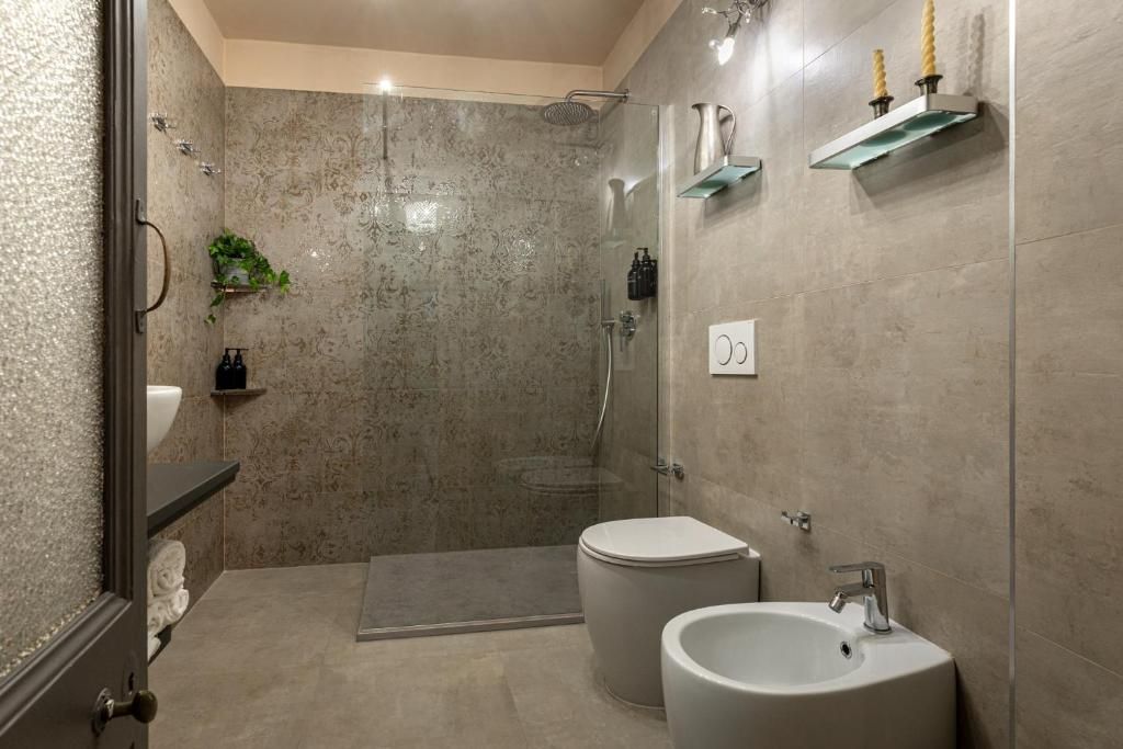 A modern bathroom with a glass-enclosed shower, a toilet, and a sink.