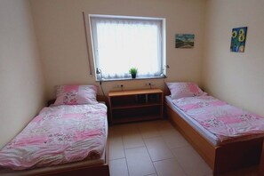 A small room with two single beds, a window with a plant, and a wall with a painting. - ||-----------------------Erdener Steps----------------------|| (Erden)