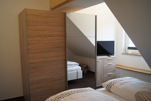 Ein Schlafzimmer mit einem Bett, einem Kleiderschrank, einem Fernseher und einem Fenster.