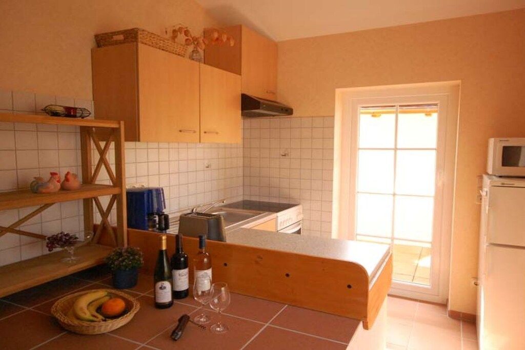 Eine Küche mit Holzausstattung, gefliestem Rücksprühen, einem Fenster und einer Mikrowelle.