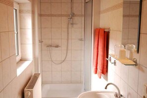 Une salle de bain avec une douche, un lavabo et un porte-serviettes.