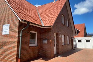 A brick building with a red-tiled roof, two windows, and a sign indicating 'Ferienhaus Anna' and 'Ferienhaus Laura'. - Holiday home in Borkum with swimming pool (Borkum)