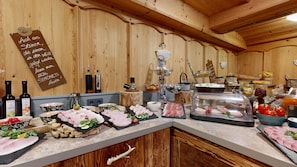 A wooden interior with a buffet setup including various meats, cheese, and fruits. - Denggenhof Apartments am Wilden Kaiser (Söll)