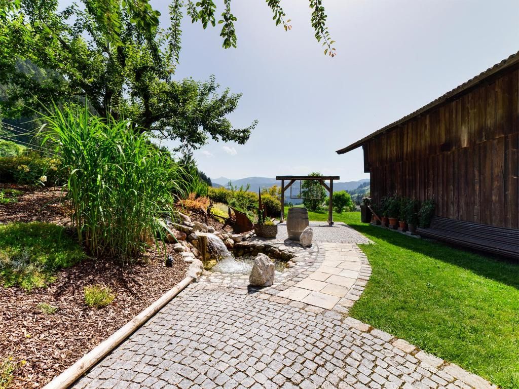 Ein gepflasterter Gartenweg führt zu einer hölzernen Struktur mit einer Pergola.