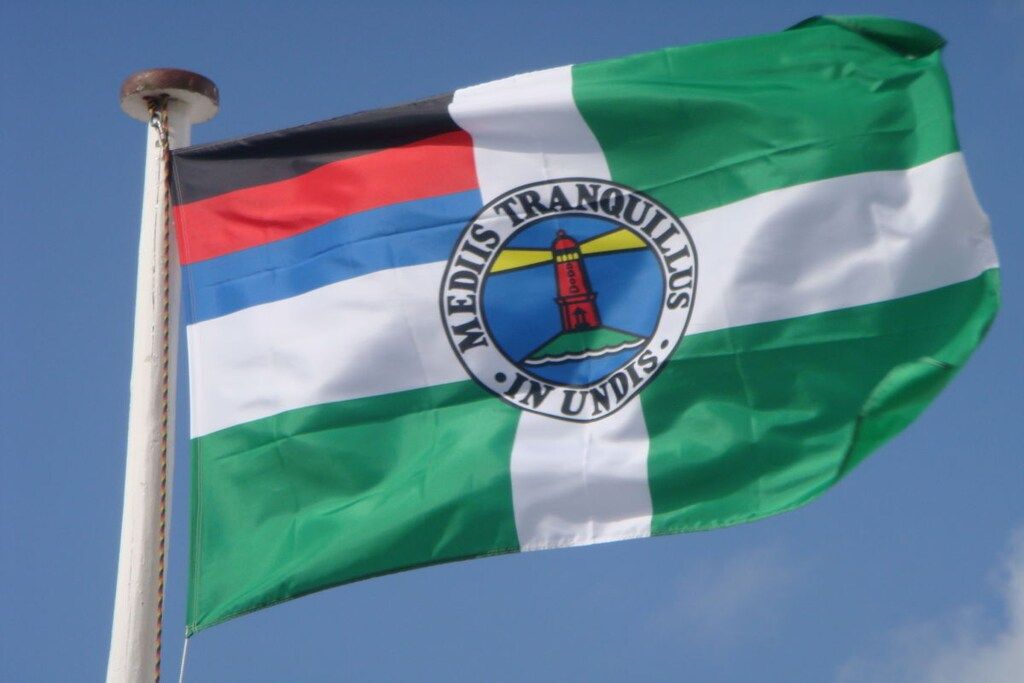 A flag with a lighthouse emblem and the text 'MEDIIS TRANQUILLO IN UNDIS.'