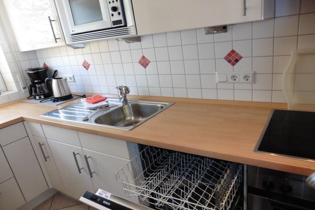 Una cocina equipada con microondas, cafetera, lavaplatos y lavamanos.