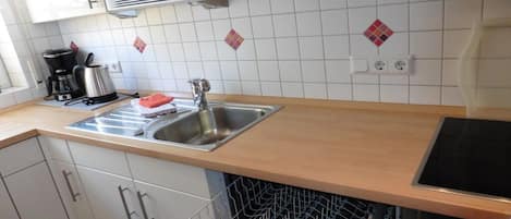 Una cocina equipada con microondas, cafetera, lavaplatos y lavamanos.