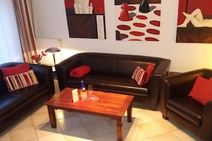 A living room with a dark leather sofa, a wooden coffee table, and a lamp. - Holiday home in Borkum with swimming pool (Borkum)