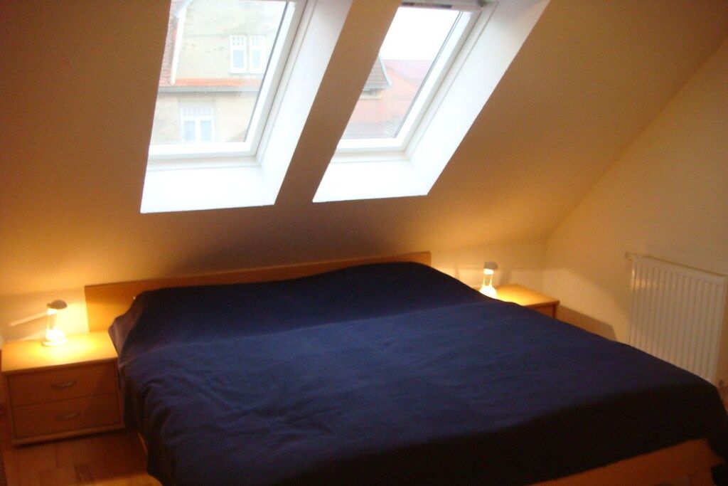 A bedroom with a bed, bedside tables, and a skylight.