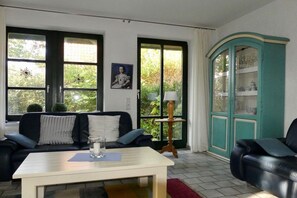 A living room with a sofa, a table, a cabinet, and a window. - Holiday Residence Oystercatcher I/No. 1 (Spiekeroog)