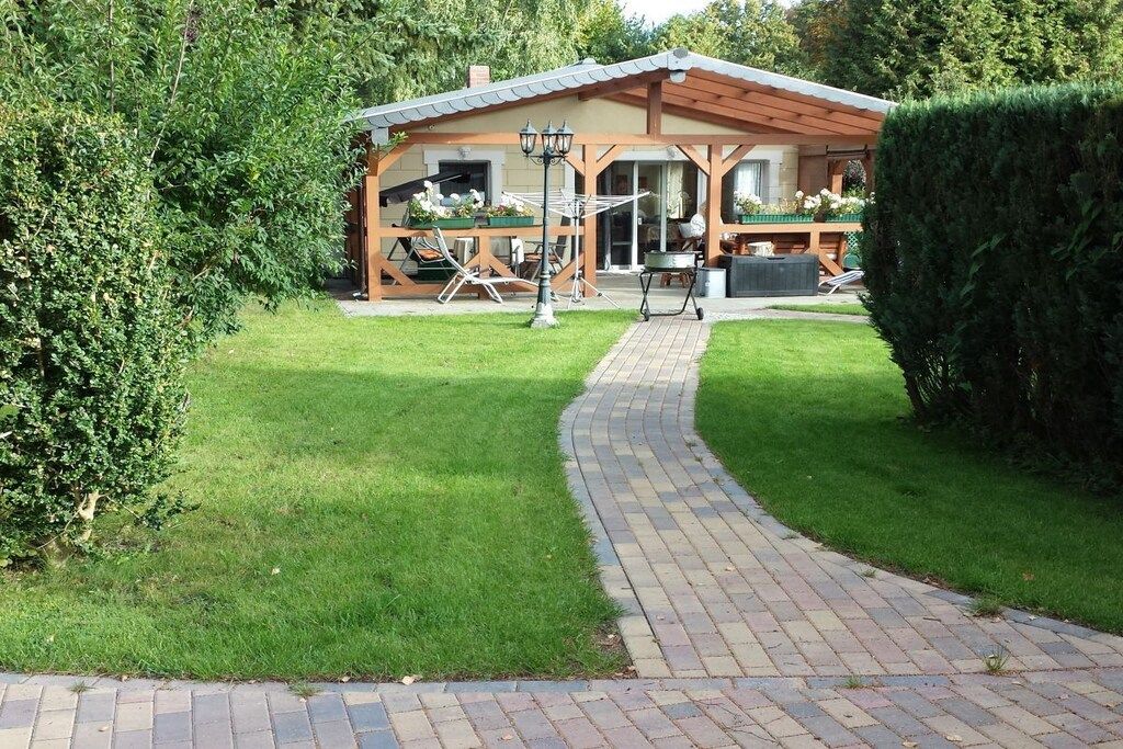 Una casa con un porche cubierto, un sendero pavimentado que conduce a ella y un césped bien cuidado.