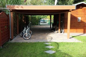 A covered outdoor area with a bicycle parked under a wooden structure. - Peter's House on the Teupitzsee Canal (Schwerin)