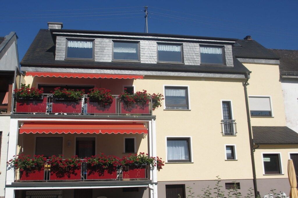 Un bâtiment à deux étages, doté d’un balcon au rez-de-chaussée et d’une lucarne à l’étage supérieur.