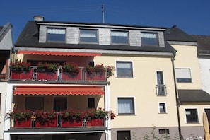 Een gebouw met twee verdiepingen, met een balkon op de begane grond en een dakkapel op de bovenverdieping.