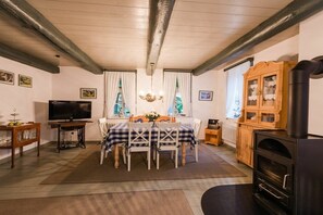 A cozy living room with a dining table, chairs, a television, a fireplace, and a cabinet. - Huus Campen - Vorderhuus (Campen)