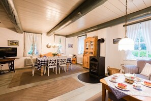 Un salon chaleureux avec une cheminée, un coin repas et un téléviseur.