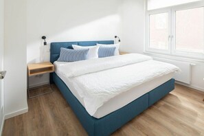 A bed with a blue headboard, white bedding, and striped pillows. - Holiday apartment in Juist with swimming pool (Juist)