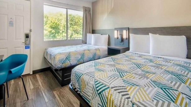 Una habitación de hotel con dos camas, un escritorio y una silla.