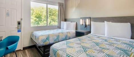 A hotel room with two beds, a desk, and a chair.