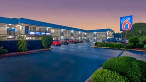 Un motel con un amplio estacionamiento y un letrero que indica el número 6.