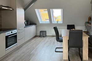 Eine moderne Küche mit Essbereich, zwei Oberlichtern und Blick auf das Dach.