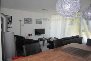 Un salon moderne comprenant un coin repas, un téléviseur à écran plat et un éclairage décoratif.