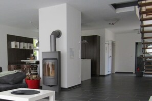Ein modernes Wohnzimmer mit Kamin, Essbereich und Küche.
