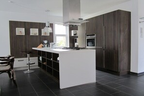 Eine moderne Küche mit dunklen Holzschränken, einer zentralen Kochinsel und einem Barhocker.