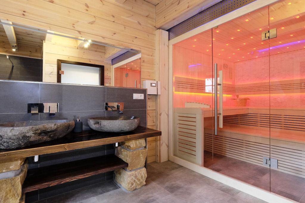 A modern bathroom with stone sinks, a wooden vanity, and a glass shower enclosure.