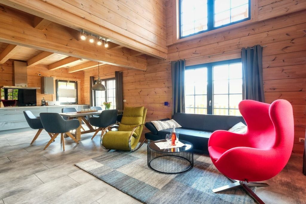 A spacious living area with a dining table, chairs, a sofa, and a red chair.