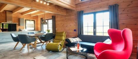 A spacious living area with a dining table, chairs, a sofa, and a red chair.