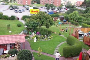 Un quartier résidentiel avec une pelouse bien entretenue, un petit jardin agrémenté d’une statue et un bâtiment au toit rouge.
