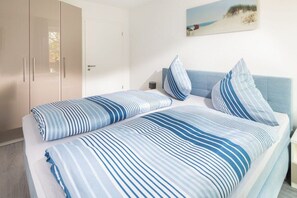 A bedroom with a bed, pillows, a nightstand, and a wardrobe. - Holiday apartment in Juist with swimming pool (Juist)
