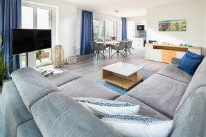 A modern living room with a sofa, coffee table, and a TV. - Holiday apartment in Juist with swimming pool (Juist)