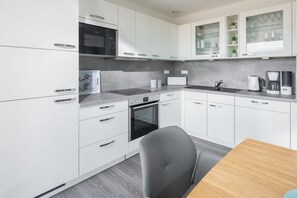 A modern kitchen with white cabinetry, a built-in oven, a microwave, and a coffee maker. - Holiday apartment in Juist with swimming pool (Juist)