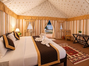 Habitación con carpa, una cama, una mesa, una silla y vistas al exterior.