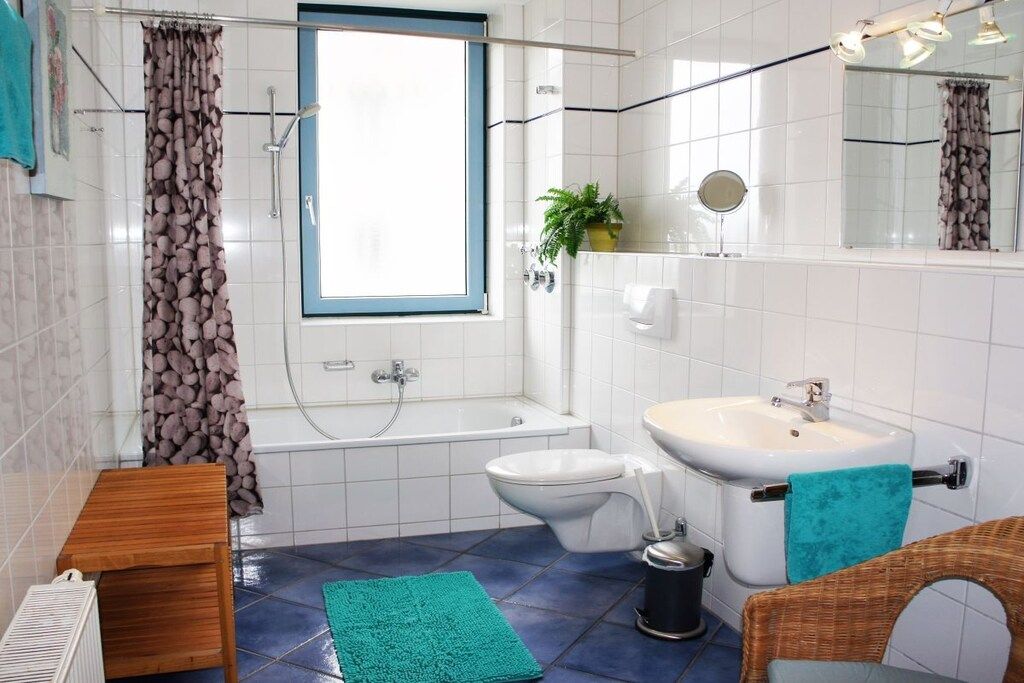 A bathroom with a bathtub, a toilet, a sink, a window, and a mirror.