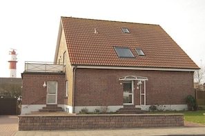 A two-story brick house with a pitched roof, a small porch, and a visible chimney. - Bekaan House on the South Beach (Borkum)