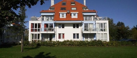 A two-story building with a red roof, white walls, and multiple balconies.